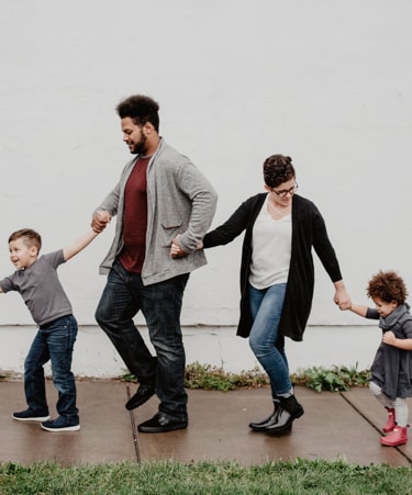 two parents with to children happy and holding each other hands.